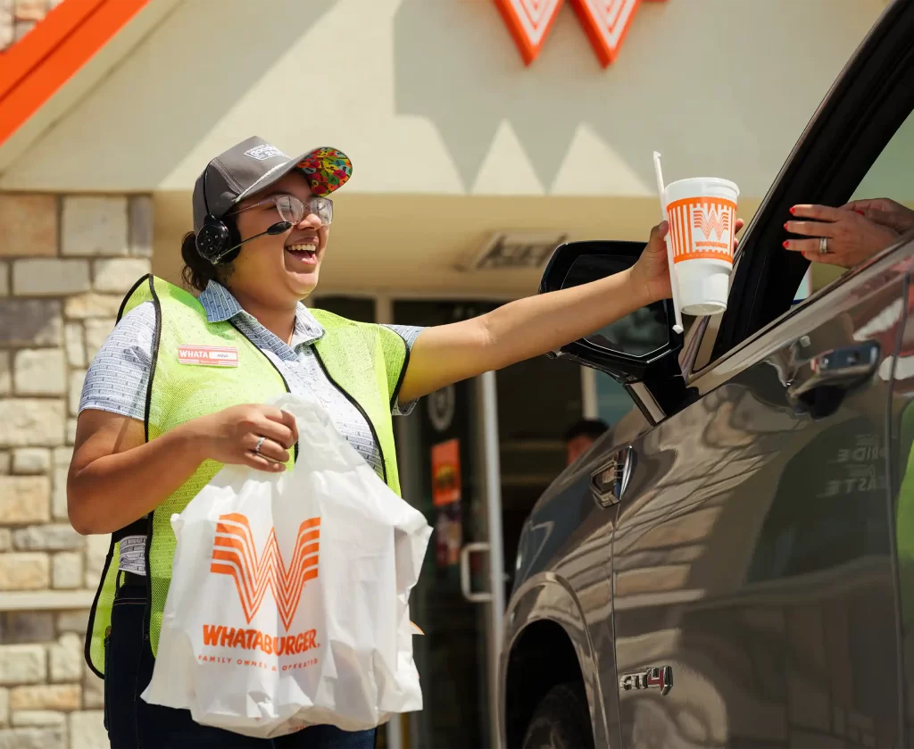 Whataburger team member serving a customer at the drive-thru window of a Mississippi Whataburger restaurant.