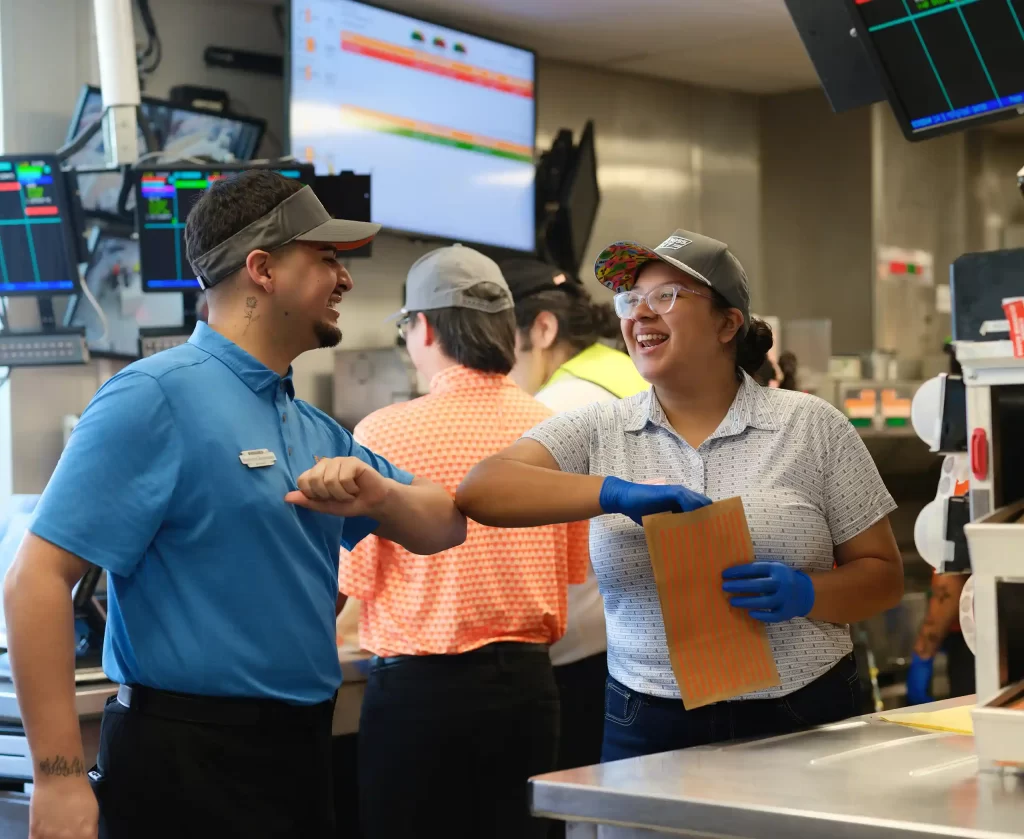 Whataburger employees collaborating inside a Mississippi restaurant during food preparation and customer service.