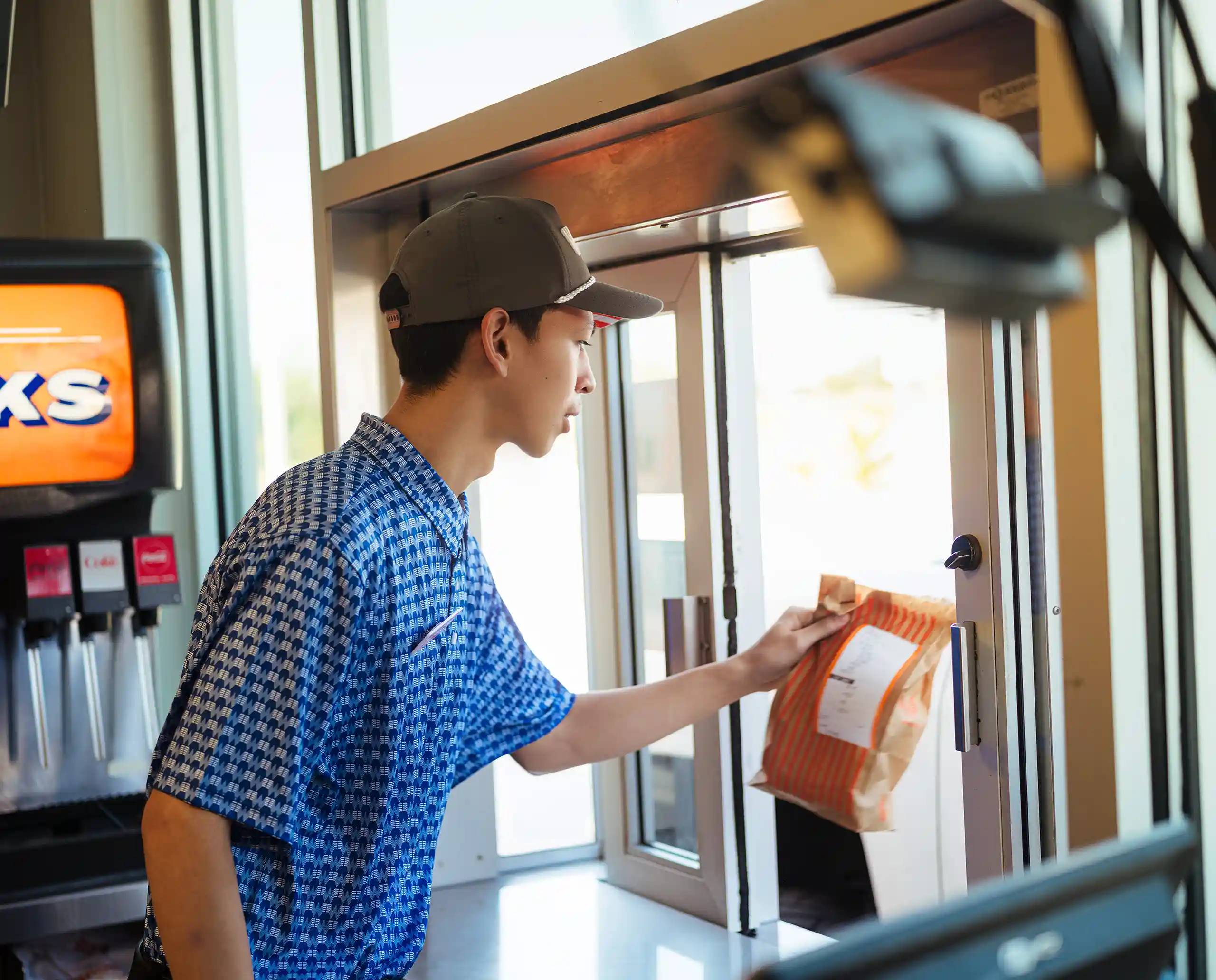 Whataburger employee handing a customer order through the drive-thru window at a Mississippi restaurant.