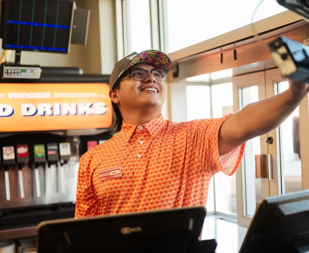 Whataburger employee assisting customers at the drive-thru station inside a Mississippi restaurant.